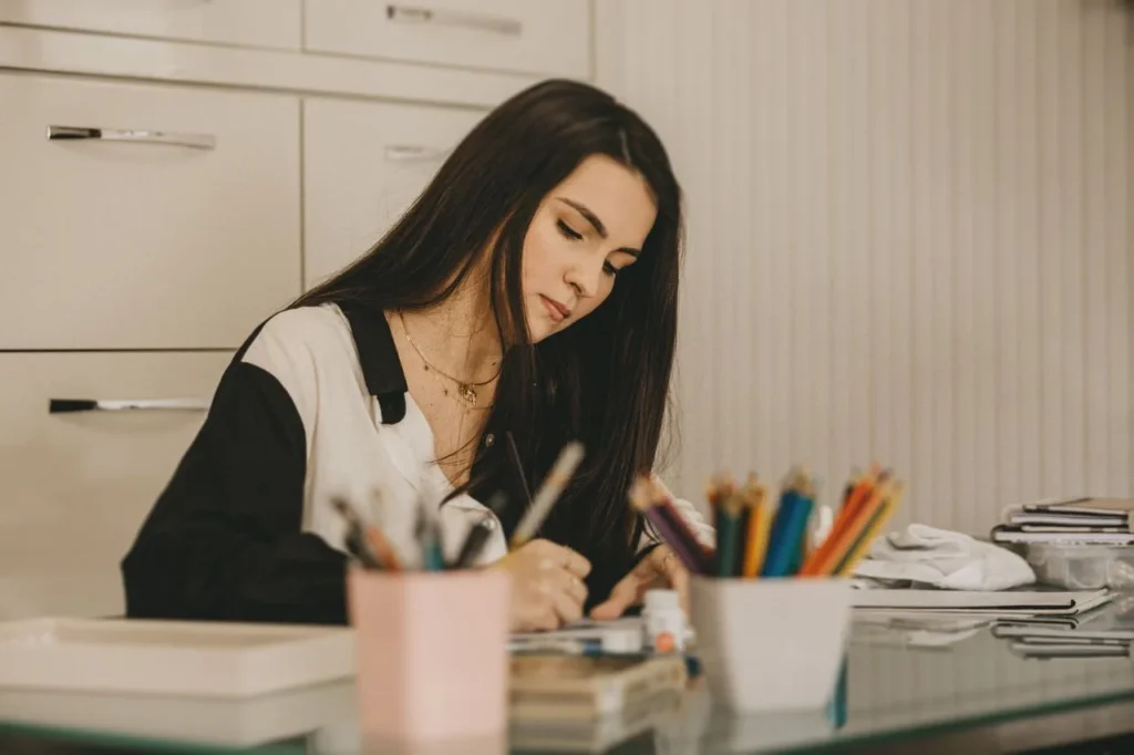 Frau arbeitet konzentriert mit Stiften und Notizen an einem Entwurf