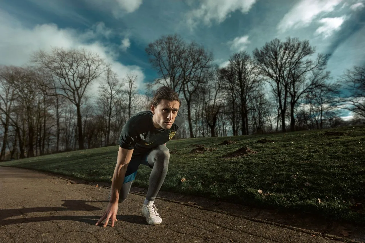 A runner is kneeling in the starting position on a path