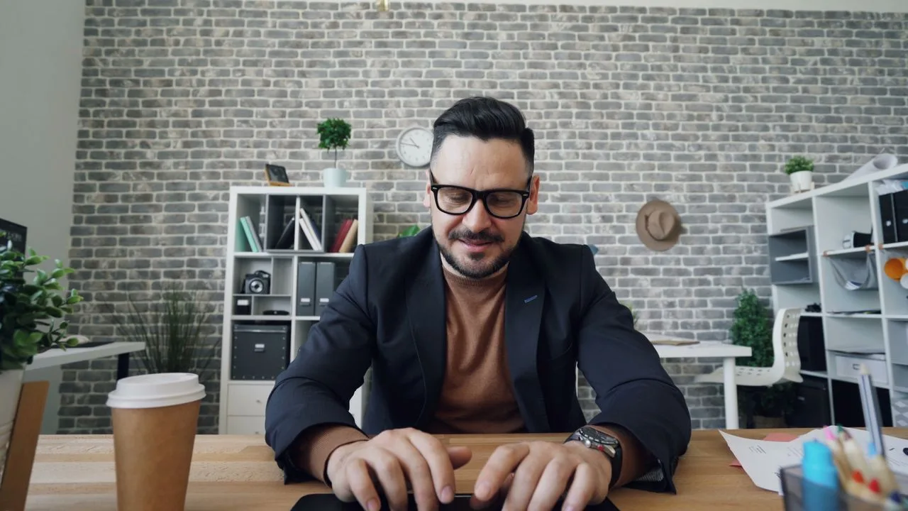 Mann sitzt nachdenklich am Schreibtisch und schaut auf seinen Laptop